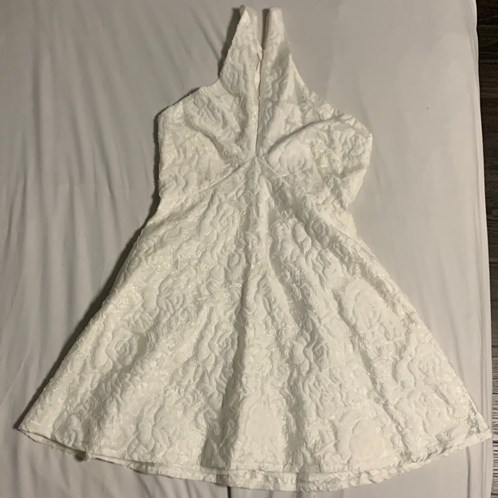 Short flower patterned white dress. Deep V-neck. Crossed adjustable back straps.